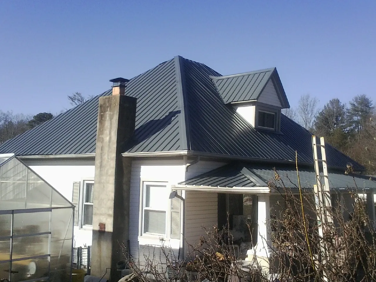 Dark blue standing seam metal roof on a white farmhouse with dormer — Slate & Tile Roof Repair by Roofing Brothers in Lavalette