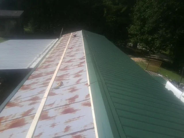 Old rusted panels beside newly installed green metal roofing — Wind Damage Roof Repair by Roofing Brothers in Lavalette