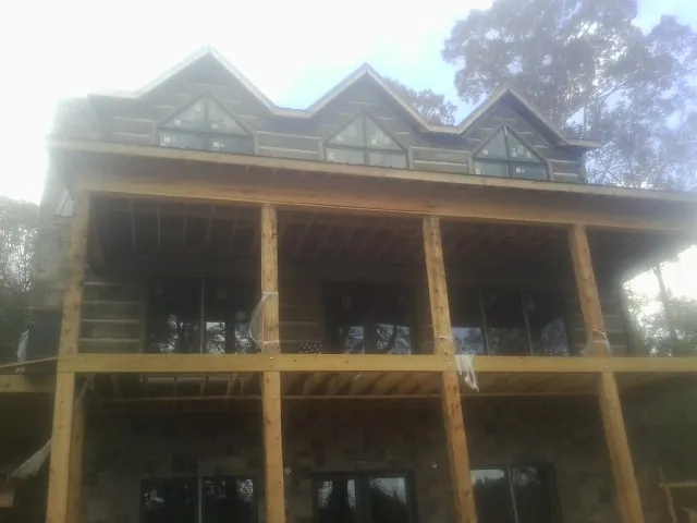 Dormers and porch framing on a large log home under construction — Roof Coating work by our crew in Lavalette