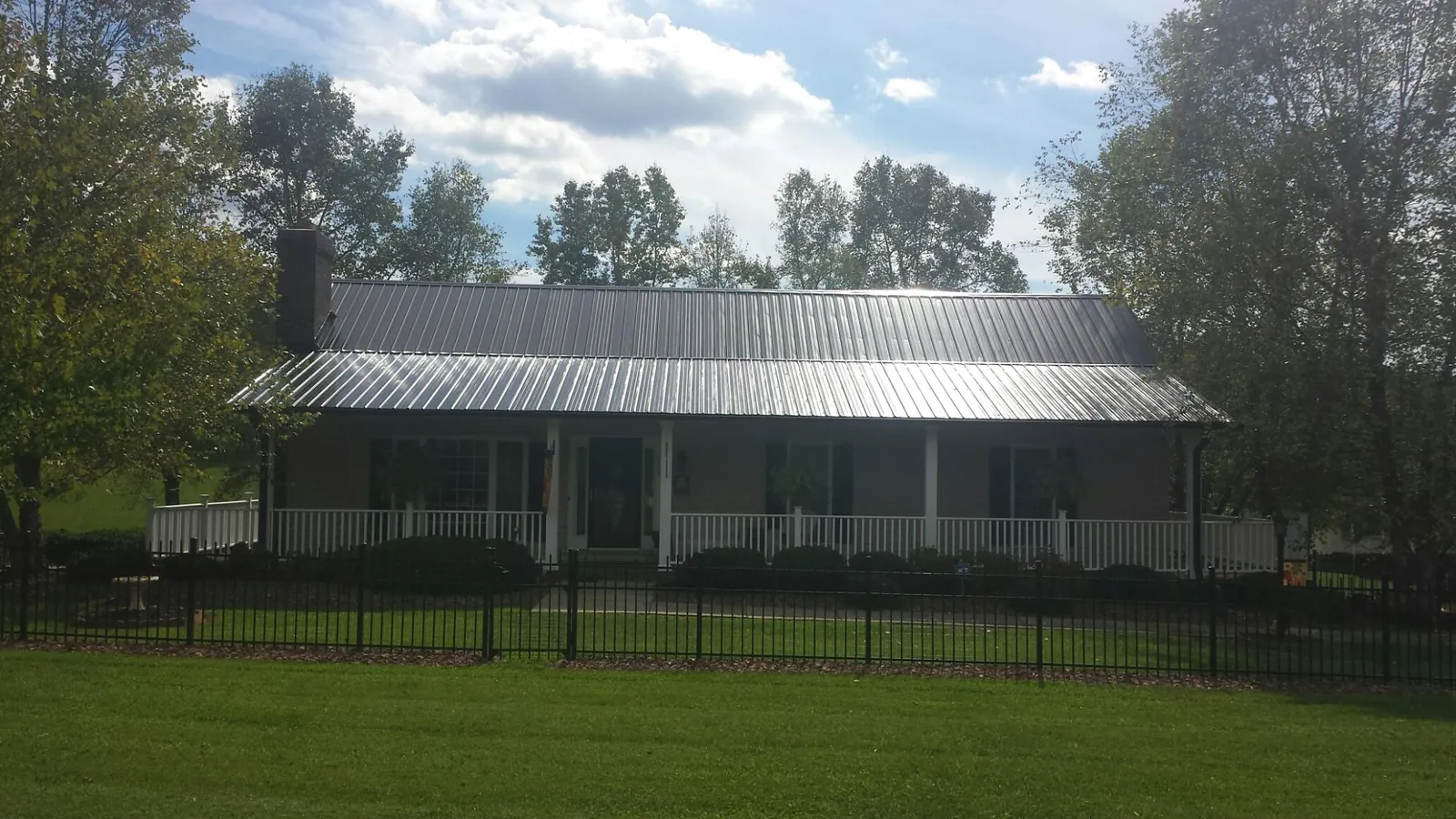 Gray metal roof on a brick ranch with a full width front porch — Gutter Guard Installation work by our crew in Lavalette
