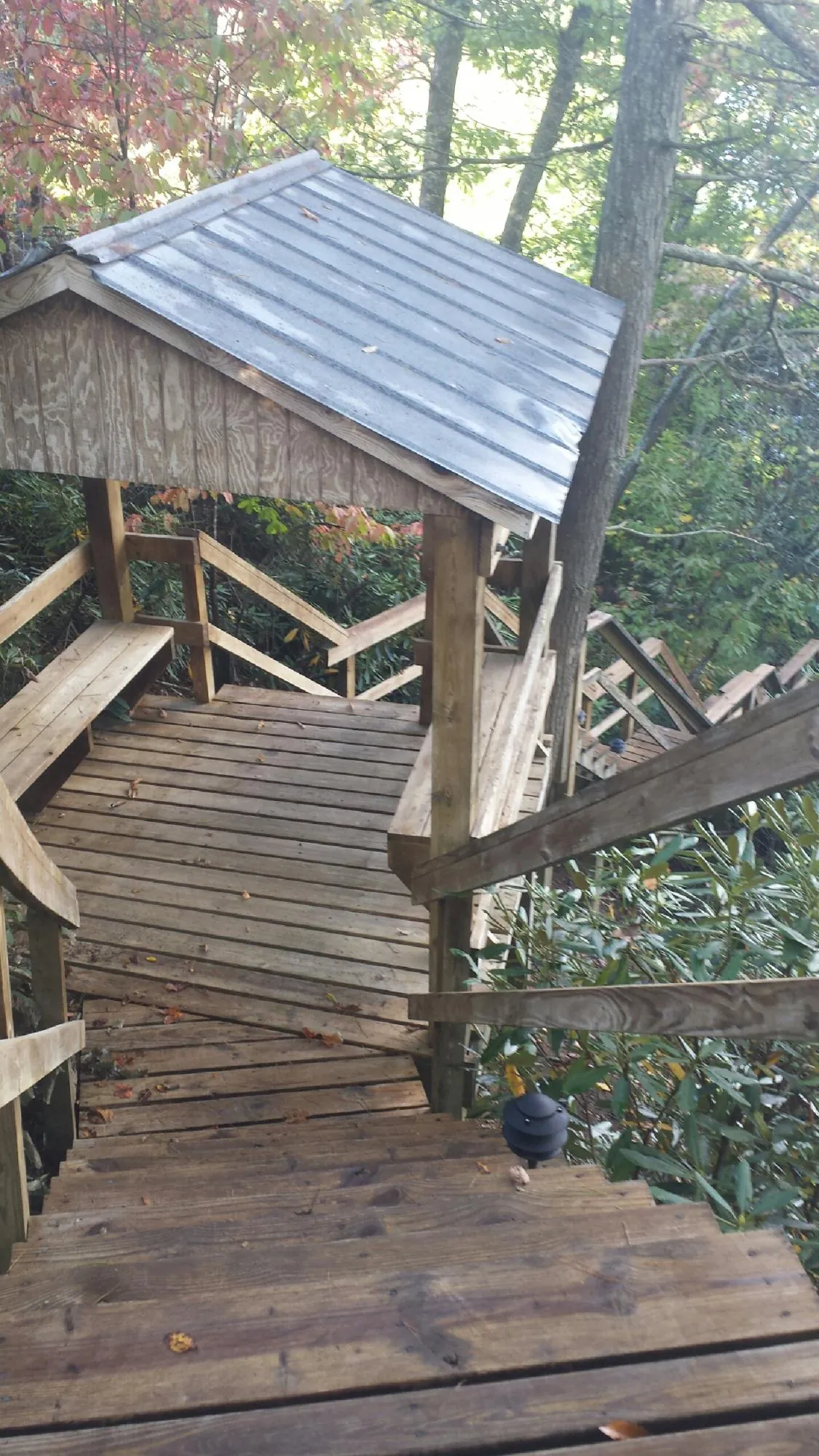 Metal roofed shelter over wooden steps on a wooded walkway — Skylight Repair & Installation work by our crew in Lavalette