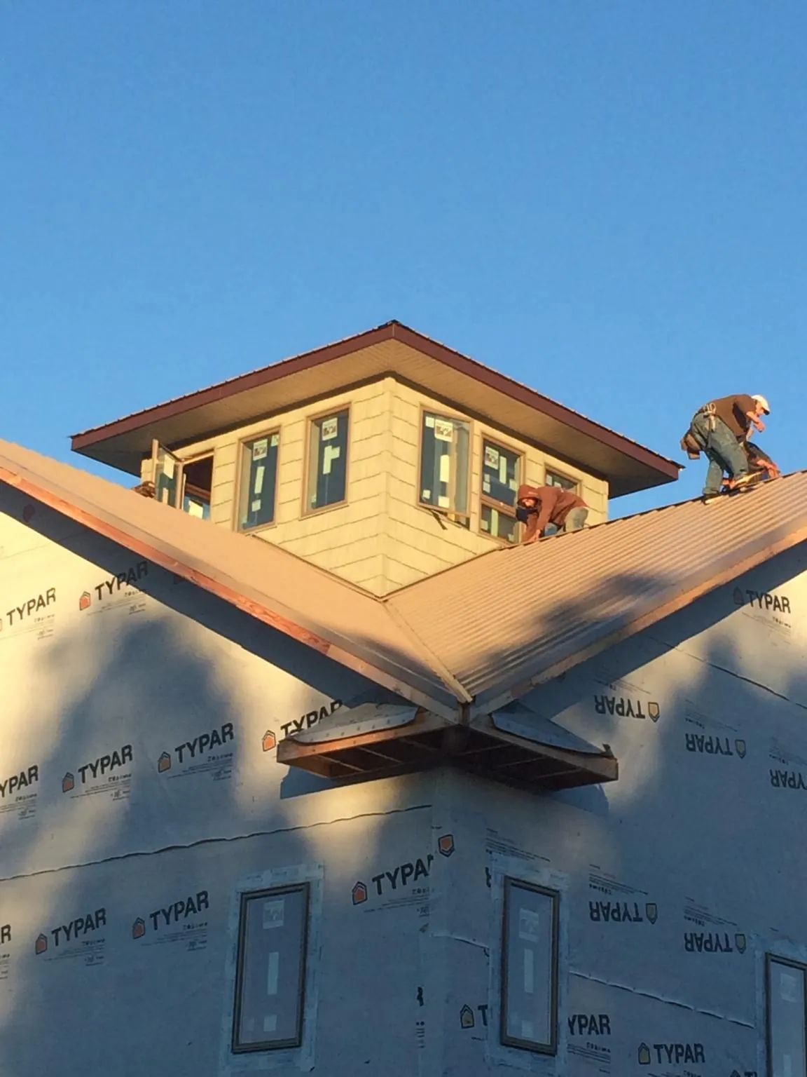 Roofers working around a rooftop cupola on a new metal roof at sunset — Roof Waterproofing in Lavalette by Roofing Brothers